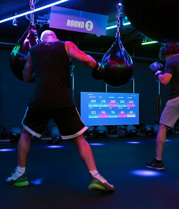 Man performing a controlled strength exercise in a modern, dark gym.