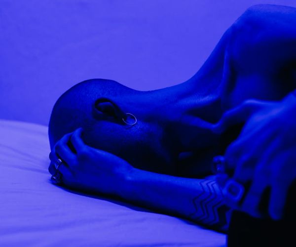 Silhouette of a man meditating with a bright blue light behind his head.